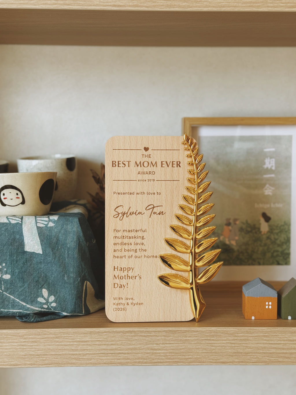 Wooden plaque with leaf design and text on a shelf with decorative items