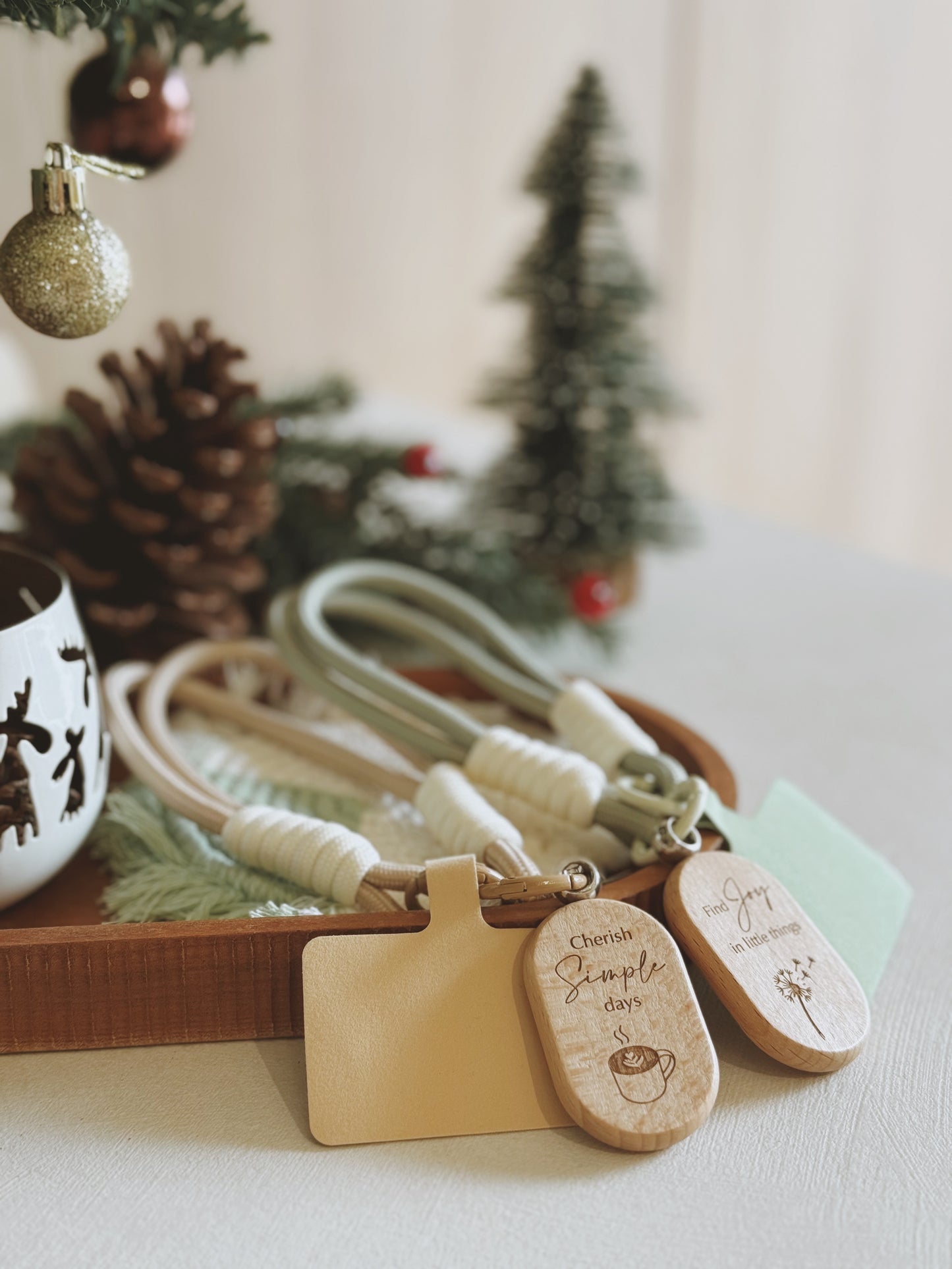 Wooden keychains with engraved text on a decorative tray with Christmas decor.